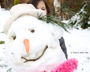 snowmanwm building a snowman with a pink scarf