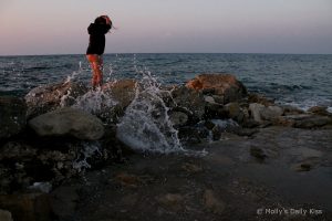 waves over the rocks around a little girl