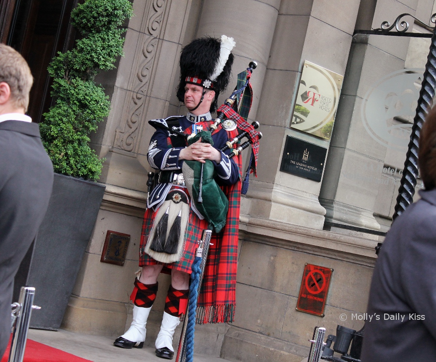 man in highland dress playing the bagpipes in edinburgh