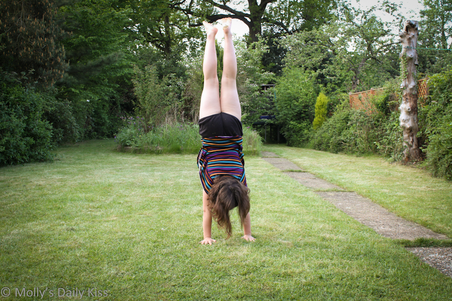 Young girl doing perfect handstand in the garden