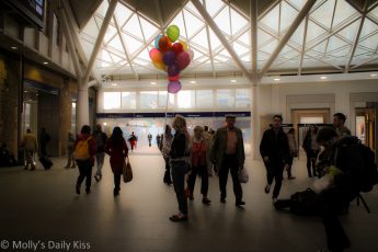 Woman with bunch of balloon in train station