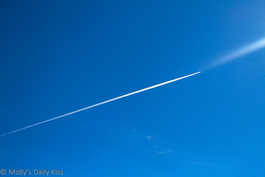 White plane trail across blue sky