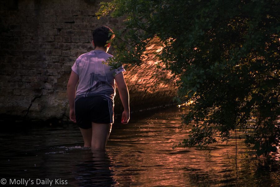 Young man walking in the river Mimram