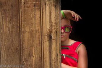 Girl peeking round door with reflection in her sunglasses
