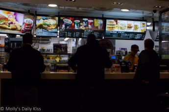Silhouettes of people waiting at fast food counter