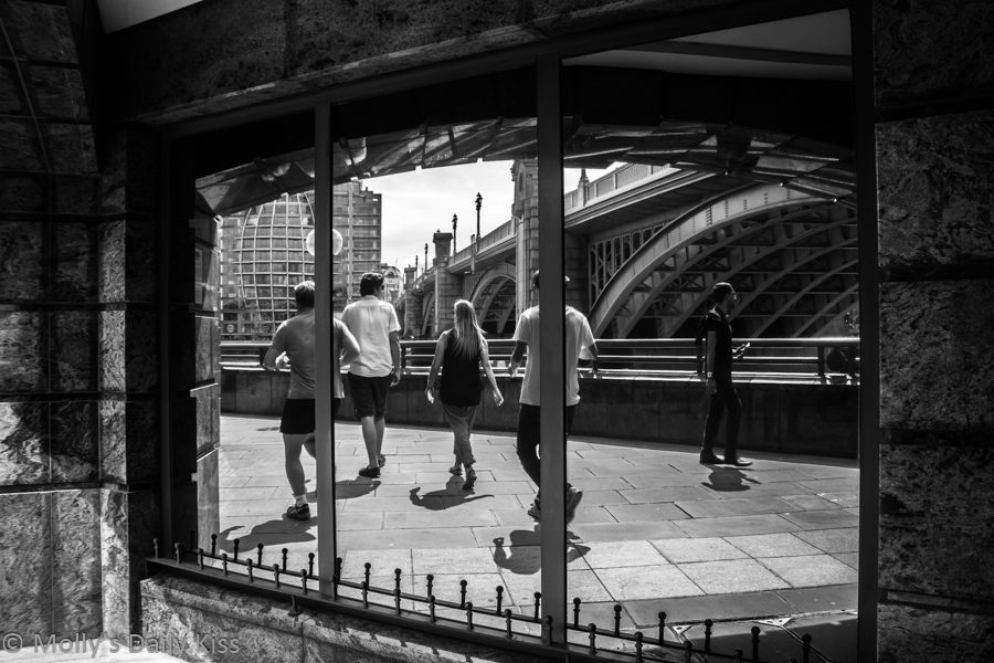 Runners on the embankment reflected in window makes a multidimensional image