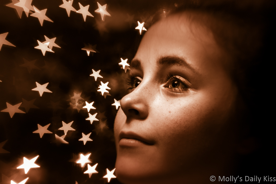 Portrait of young girl in front of Christmas tree stars taken with Lens Baby