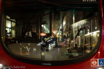 reflection in the front window of a london bus at night