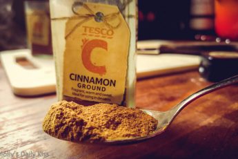 Cinnamon piled on teaspoon in front of pot of cinnamon
