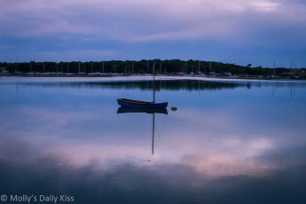 Lone sailing boat moored on very still water in Yarmouth Isle of Wight