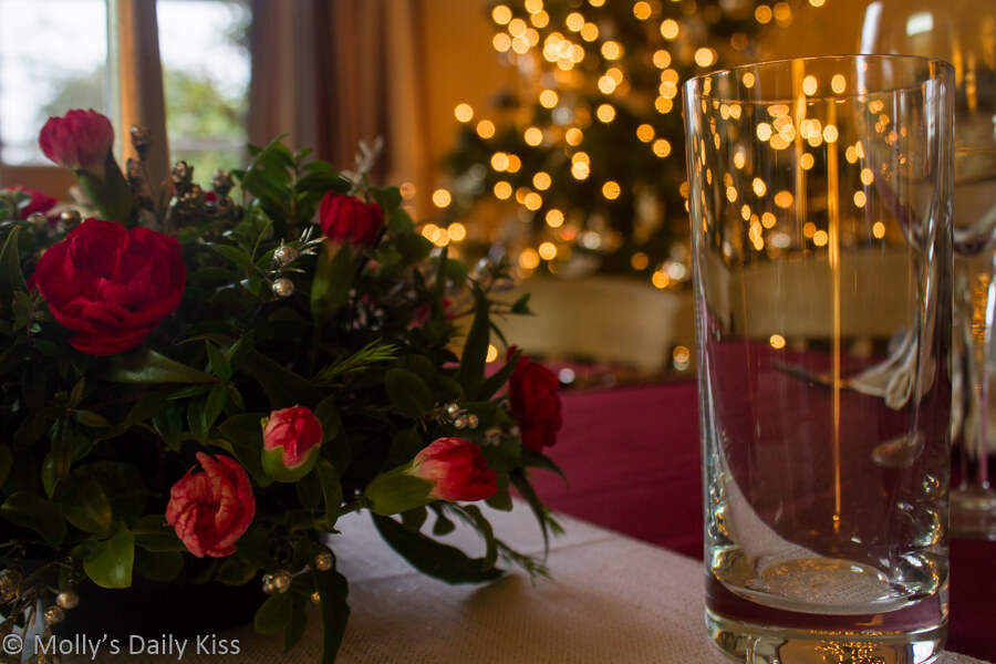 Christmas table flower decorations with bokeh christmas tree in the backgroun