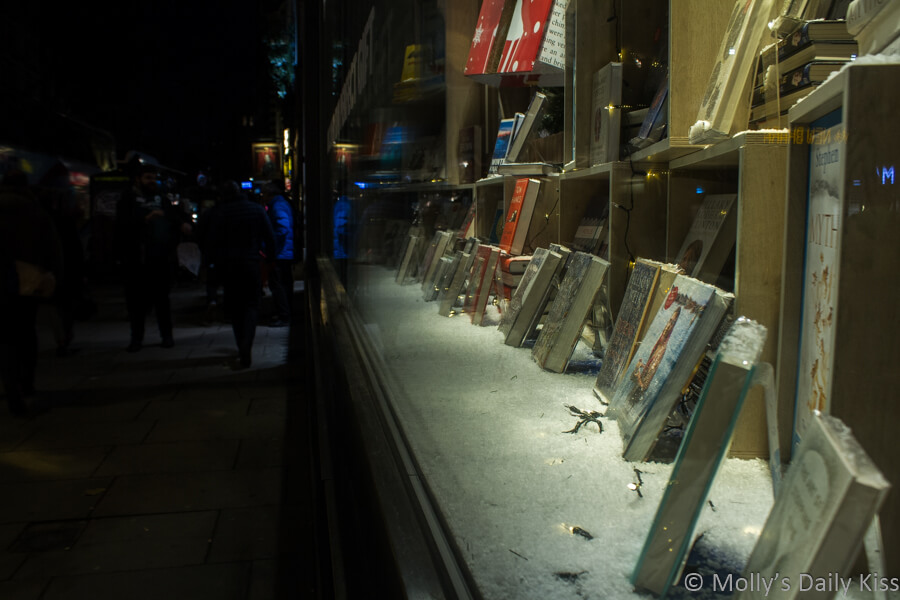 Reflection of people on the street in London book shop window that contains books which are silent voices