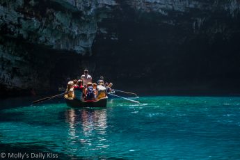 people lit up in sunlight in a boat in the blue waters of a cave