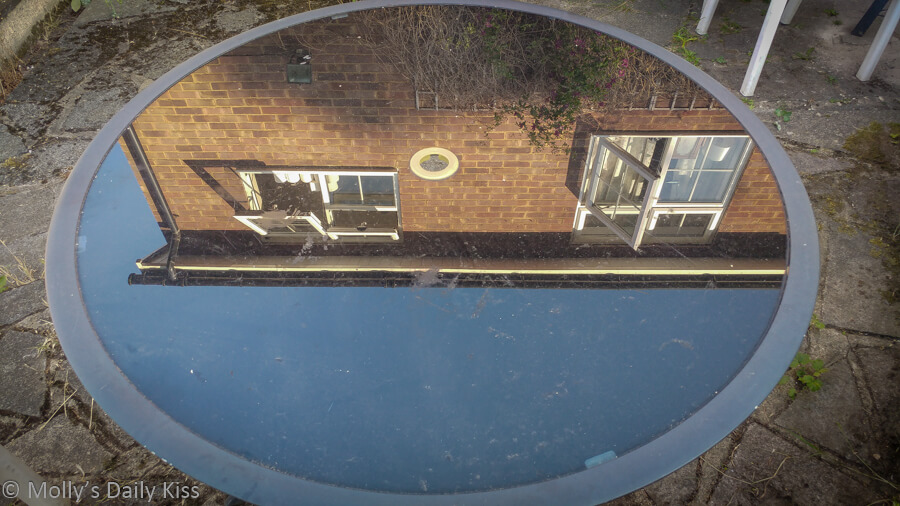 reflection of house in glass table top of garden table