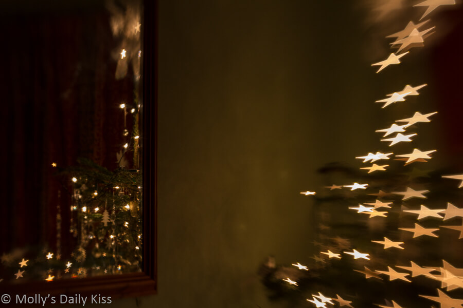 Relfection of Christmas tree in mirror with tree showing bokeh stars