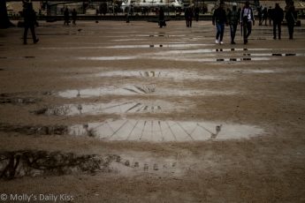 reflection of place du la concord ferris wheel in rain puddles in paris
