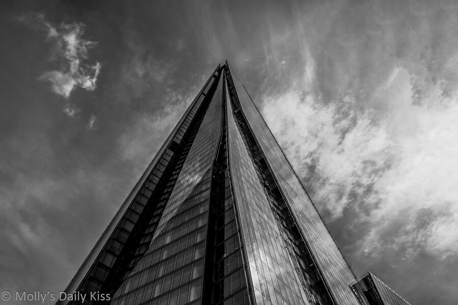 Looking up the Shard landmark in london to whispy clouds in the sky in black and white