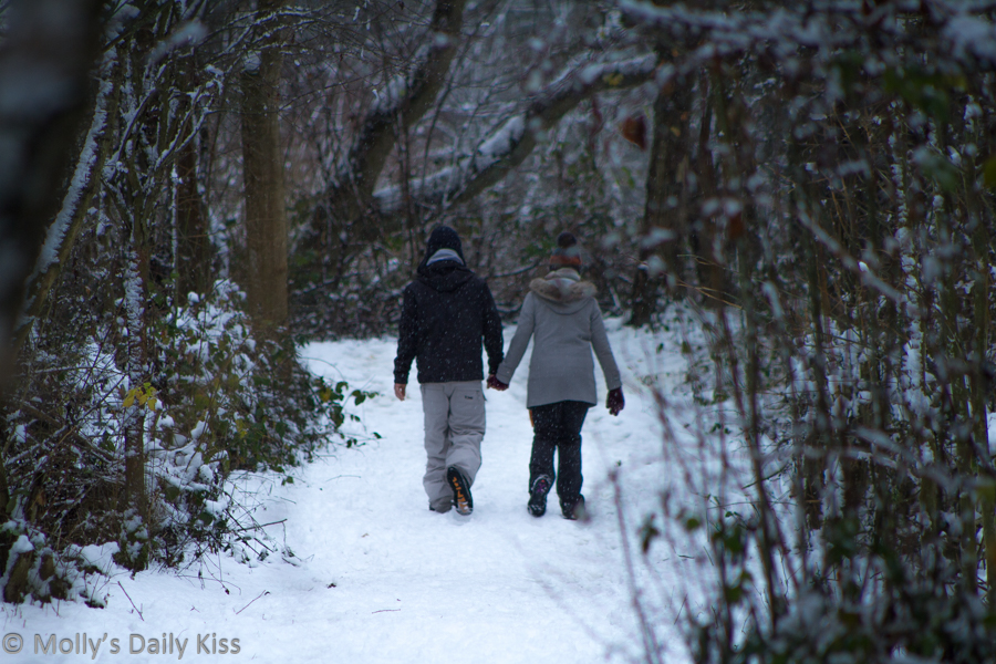 Couple walking through snow in woods