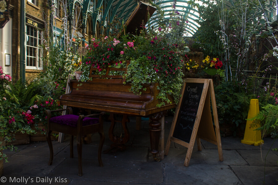 Old piano in covent garden covered in flowers