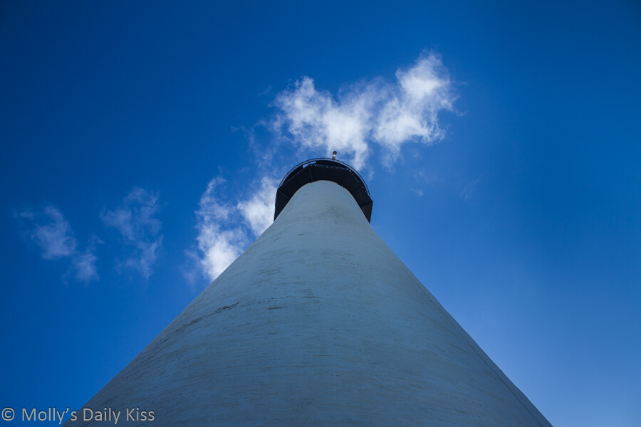 looking up a lighthouse to bright blue skies