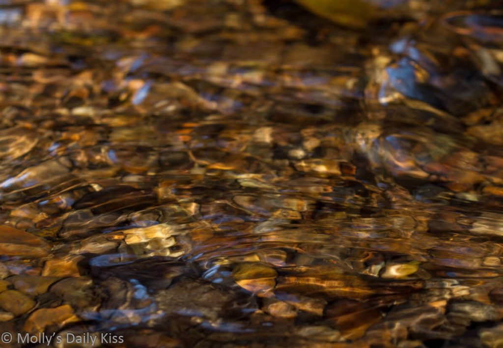 Water running over pebbles in river