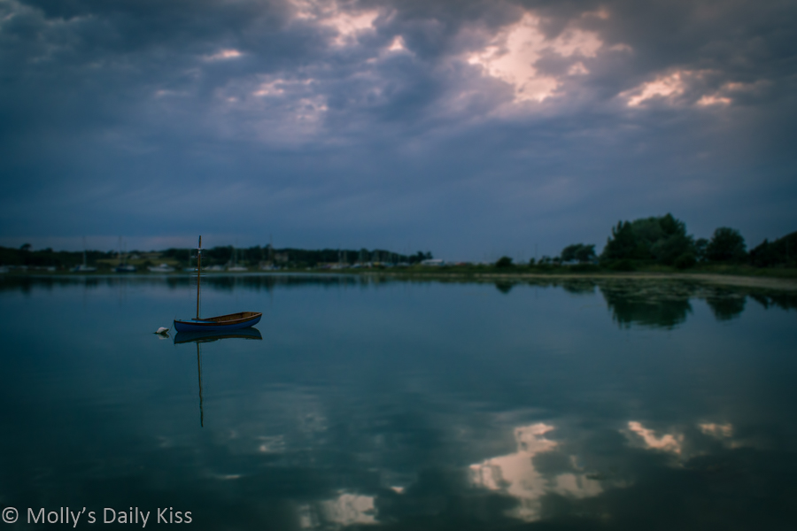 Dignity, little blue boat moored in water with clouds relfected