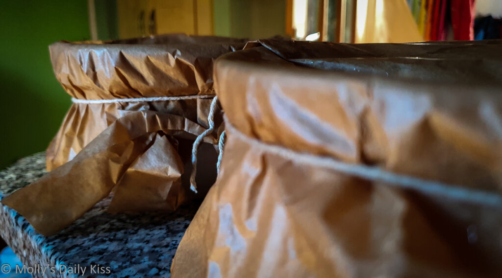 Christmas Puddings in their pudding bowls and wrapped up on baking paper