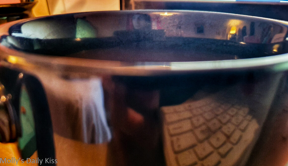 Coffee cup with desk reflected in the edge