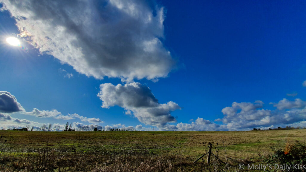 big blue sky with white fluffy clouds above fields