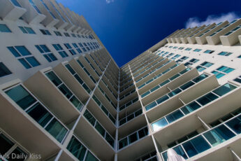 Looking up at lofty white tall building to blue sky above