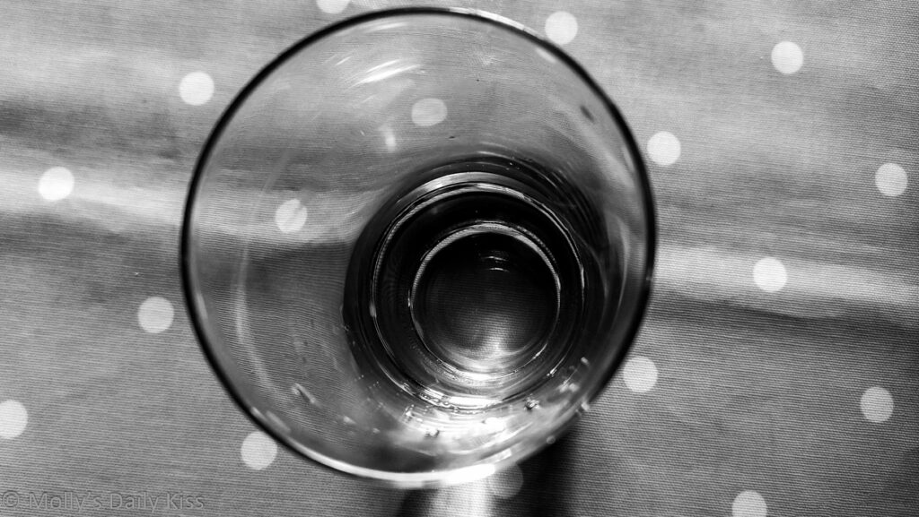Looking down into empty glass sitting on polka dot table cloth edited in black and white