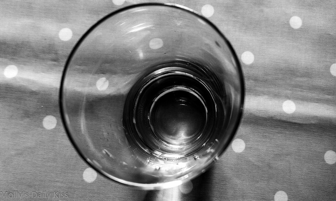 Looking down into empty glass sitting on polka dot table cloth edited in black and white