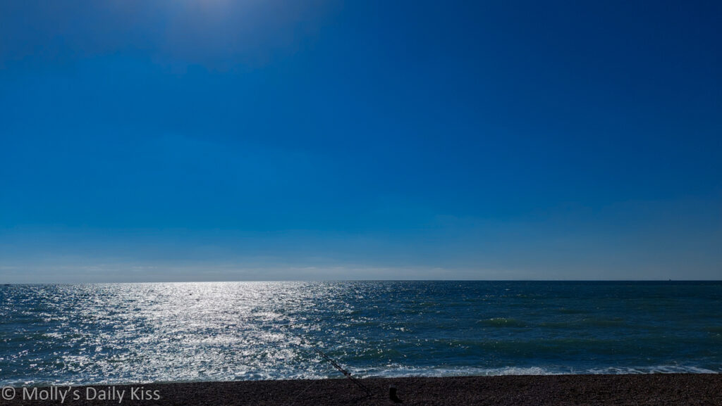 Blue water of the sea meeting the blue of the sky with sun reflected on the water
