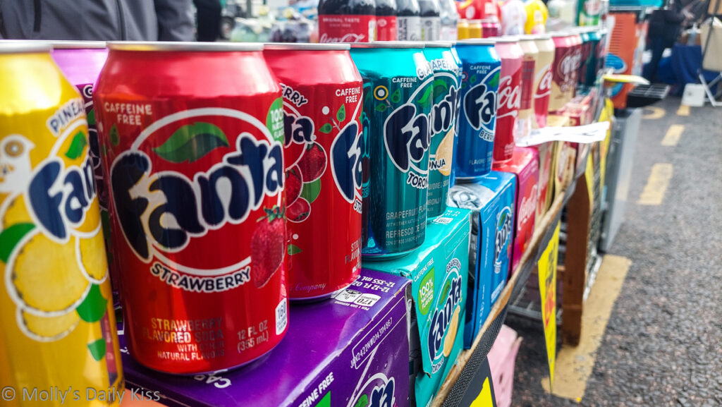 Choice of colourful fanta drinks in cans all lined up on market stall