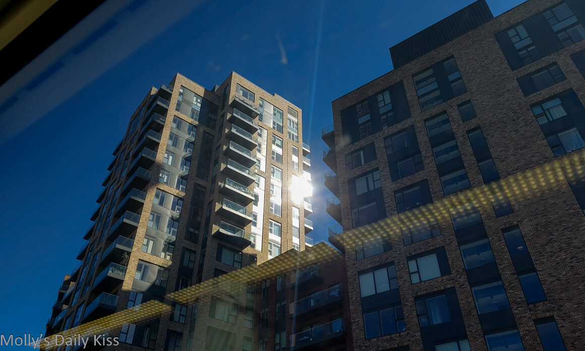 looking up at apartmenr building from the train with sun bouncing off the windows tells a story